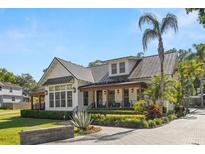 Charming two-story home featuring manicured landscaping, a metal roof, and a welcoming covered porch at 5610 N River Shore Dr, Tampa, FL 33603