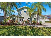 Charming two-story home with lush tropical landscaping, a circular window and an attached two car garage at 640 Kenneth Way, Tarpon Springs, FL 34689