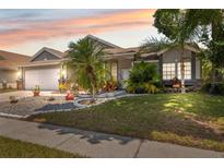 Charming single story home featuring a well maintained lawn and meticulously landscaped yard with tropical palms at 7903 Lake Placid Ln, Trinity, FL 34655