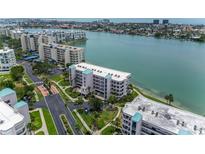 Beautiful waterfront condo building with manicured landscaping and serene water views at 8000 Sailboat Key S Blvd # 202, St Pete Beach, FL 33707