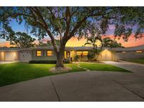 Charming single-story home with a well-manicured lawn, mature tree and attached garage at sunset at 12453 138Th N St, Largo, FL 33774