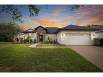 Charming home with a manicured lawn, stone accents, and a brick driveway at sunset at 14019 Nighthawk Ter, Lakewood Ranch, FL 34202
