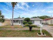 Charming single-story home featuring a manicured lawn, solar panels, and inviting curb appeal at 1516 Roundtree Rd, Holiday, FL 34690