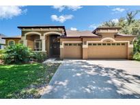 Charming, single-story home with a manicured lawn and spacious three-car garage on a sunny day at 15724 Ibisridge Dr, Lithia, FL 33547