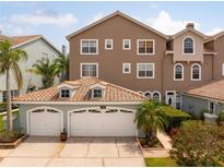Inviting exterior view of a multi-story townhouse with a two-car garage and tile roof at 1750 Arabian Ln, Palm Harbor, FL 34685