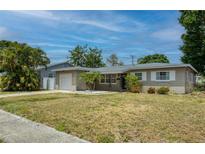 Charming single-story home with a well-maintained lawn, complemented by lush trees and tropical landscaping at 211 80Th N Ave, St Petersburg, FL 33702