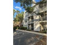 Condo building featuring balconies and outdoor living, lush landscaping and ample parking at 3260 Haviland Ct # 202, Palm Harbor, FL 34684