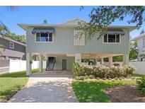 Charming two-story home featuring a stilt foundation, a driveway, and a beautifully landscaped yard at 4027 Alabama Ne Ave, St Petersburg, FL 33703