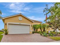 Lovely yellow single-story home featuring a brick driveway and attached two-car garage at 4949 Marble Springs Cir, Wimauma, FL 33598
