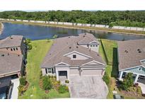 Stunning aerial view of a modern home with a paved driveway, well-maintained landscaping, and a tranquil lake view at 5477 Wayfarer Ave, Apollo Beach, FL 33572