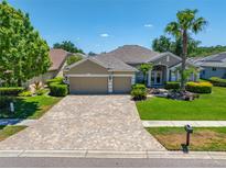 Beautiful home featuring a three-car garage, paver driveway, manicured lawn, and mature landscaping at 6104 Cognac Cir, Lutz, FL 33558