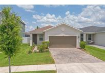 Charming single-story home featuring a well-manicured lawn, lush landscaping, and a brick-paved driveway at 11830 Brighton Knoll Loop, Riverview, FL 33579