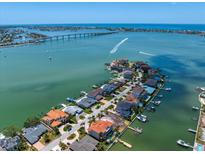 Stunning aerial view of waterfront homes, featuring boat docks and clear blue water in the distance at 14 Sunset Bay Dr, Belleair, FL 33756