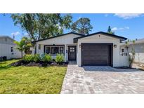 Charming home with a well-manicured lawn, paver driveway, and dark trim accents at 1710 Shore Acres Ne Blvd, St Petersburg, FL 33703
