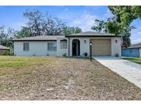 Charming single-story home with an attached garage, long driveway, and well-maintained front yard at 180 Rusk Cir, Spring Hill, FL 34606