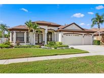 Stunning single-story home with a three-car garage, well-manicured lawn, and lush tropical landscaping at 19830 Strathmore Pl, Land O Lakes, FL 34638
