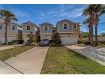 Charming townhomes featuring two-car garages, beautiful landscaping, and inviting curb appeal with lovely palm trees at 2013 Sunset Wind Loop, Oldsmar, FL 34677