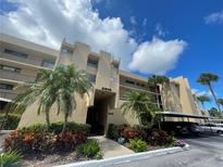 Condo building exterior with well-maintained landscaping, mature palms, and covered parking at 2615 Cove Cay Dr # 408, Clearwater, FL 33760
