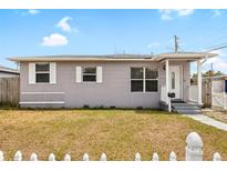 Charming gray home featuring a tidy yard, white picket fence, and welcoming front porch at 2728 39Th N Ave, St Petersburg, FL 33714