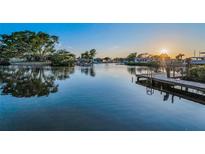 Scenic waterfront view with a wooden dock, calm water, and a beautiful sunset backdrop enhances the property's appeal at 4772 Dover Ne St, St Petersburg, FL 33703