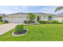 Charming single-story home featuring a well-manicured lawn, tropical plants, and a two-car garage at 6332 35Th Avenue E Cir, Palmetto, FL 34221