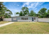 Charming single-story home with light blue siding, white trim, green lawn and a fenced yard at 6601 13Th N St, St Petersburg, FL 33702