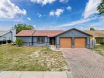 Charming single-story home featuring a two-car garage, brick driveway, and well-kept lawn at 7237 Bramblewood Dr, Port Richey, FL 34668