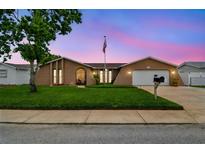 Charming single-story home featuring a lush lawn, attached garage, and inviting curb appeal with an American flag at 8225 Medford Dr, Port Richey, FL 34668