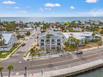 An exterior showcases a three-story beach house, white columns, and balconies, offering stunning coastal living at 1104 Pass A Grille Way, St Pete Beach, FL 33706