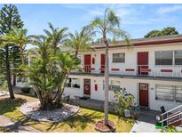 Charming condo featuring red entry doors, tropical landscaping, and well-maintained grounds at 1900 58Th N Ave # 26, St Petersburg, FL 33714