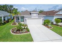 Charming single-Gathering home featuring a well-manicured lawn, landscaped garden beds, and a two-car garage at 3603 Woodmont Dr, Parrish, FL 34219