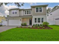 Charming two-story home featuring manicured lawn, fresh landscaping, and a light gray color palette at 3614 W Platt St, Tampa, FL 33609