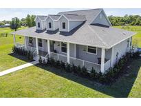 Inviting gray home with a charming wraparound porch, white railings and dormer windows at 7627 Artifact Dr, Zephyrhills, FL 33541