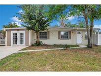Charming single-story home featuring a manicured lawn, complemented by mature trees and a welcoming facade at 10381 108Th Ave, Largo, FL 33773