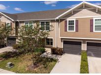 Inviting townhome featuring a well-manicured lawn, attached garage, and neutral-toned siding with charming accent shutters at 10436 Rivercrest Dr, Riverview, FL 33578