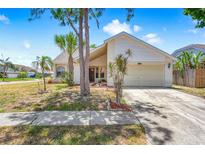 Charming single-story home with a two-car garage, lush landscaping, and a well-manicured lawn on a sunny day at 12002 Peony Ct, Tampa, FL 33635