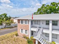 Condo exterior featuring a brick facade, white railings, and staircase leading to the upper level units at 128 Brandy Wine Dr, Largo, FL 33771