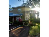 Charming townhome featuring lush landscaping, covered entrance, and well-maintained exterior at 13020 Lorna Pl, Tampa, FL 33618