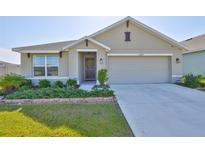 Charming single-story home featuring a well-maintained lawn, landscaped garden beds, and a two-car garage at 16704 Sunburst Lake St, Wimauma, FL 33598