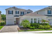 Beautiful two-story home featuring a well-manicured lawn, lush landscaping, and a charming red door at 18017 Ramble On Way, Land O Lakes, FL 34638