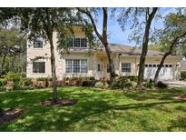 Charming two-story home with a well-manicured lawn and lovely landscaping in front at 2175 Oak Forest Ln, Palm Harbor, FL 34683