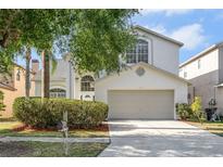 Charming two-story home featuring a two-car garage, arched windows, and mature landscaping at 27330 Coral Springs Dr, Wesley Chapel, FL 33544