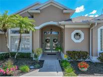 Inviting front entrance with arched entryway, double doors with decorative wreaths, and lush tropical landscaping at 2908 89Th E Ave, Parrish, FL 34219
