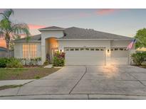 Inviting one-story home featuring a three-car garage, lush landscaping, and a well-manicured lawn at 4214 Canongate Ct, Spring Hill, FL 34609