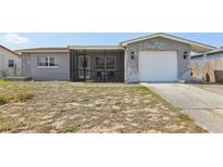 Charming home with a screen-enclosed front porch, stone accents, a single-car garage and modest landscaping at 8330 Moulton Dr, Port Richey, FL 34668