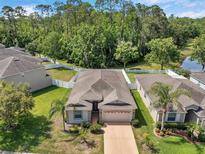 An aerial view of a single-story home with a well-manicured lawn, surrounded by lush greenery and a white picket fence at 12831 White Bluff Rd, Hudson, FL 34669