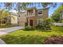 Two-story tan house with a stone pillar front porch, attached garage, and landscaped yard at 19101 Marisa Ridge Pl, Tampa, FL 33647