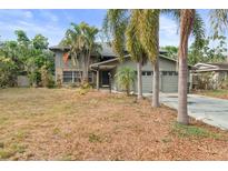 Two-story home showcasing a stone and siding facade, palm trees, and a two-car garage at 2493 6Th Sw Ave, Largo, FL 33770