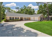 Inviting single-story home with mature trees, a large driveway, and a well-manicured lawn at 3906 Floyd Rd, Tampa, FL 33618