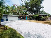 Charming home with a colorful flowering tree, brick driveway, and a light blue front door at 6429 Gulfport Blvd. South Blvd, South Pasadena, FL 33707